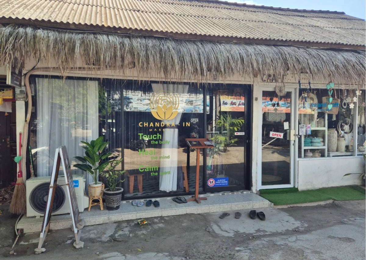 The storefront of Chandra In Spa, featuring a thatched roof, large glass windows, and a wooden sign stand outside the entrance.