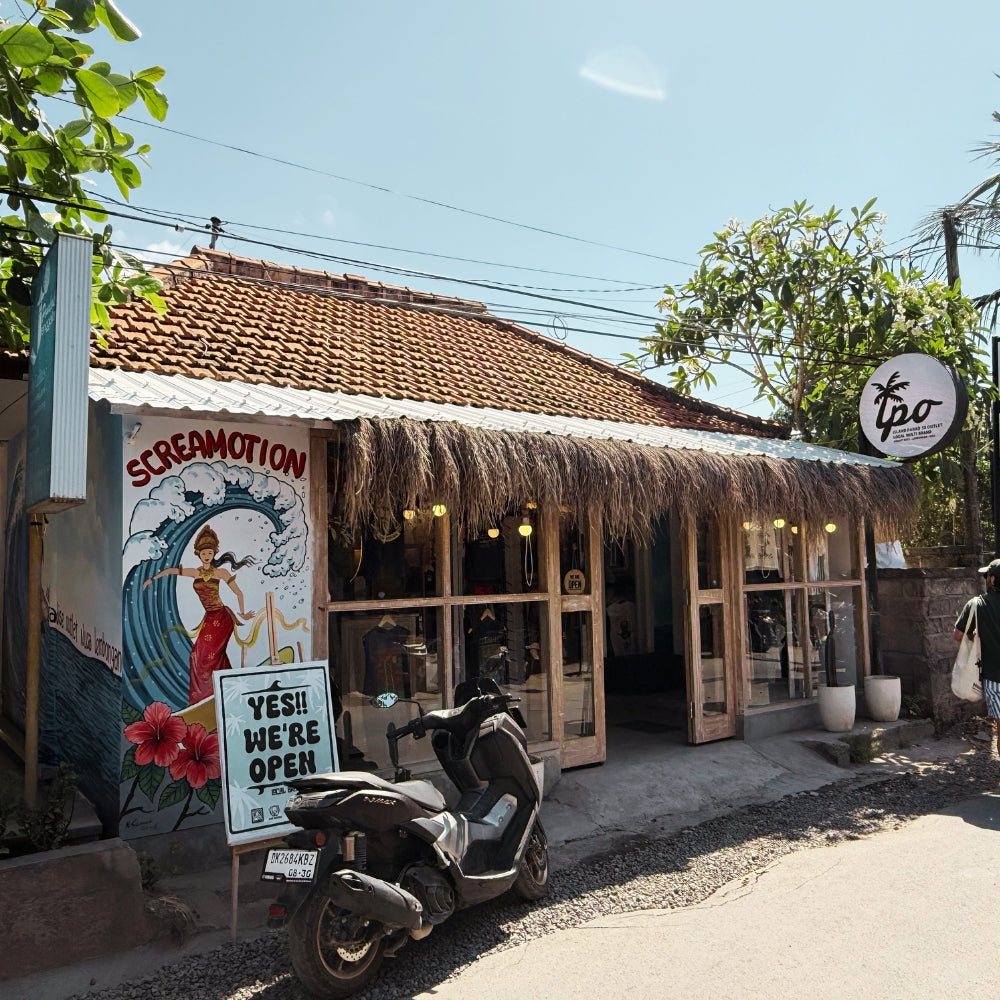 Storefront of Island Paradise in Nusa Lembongan with a thatched roof, outdoor seating area, and promotional signs.
