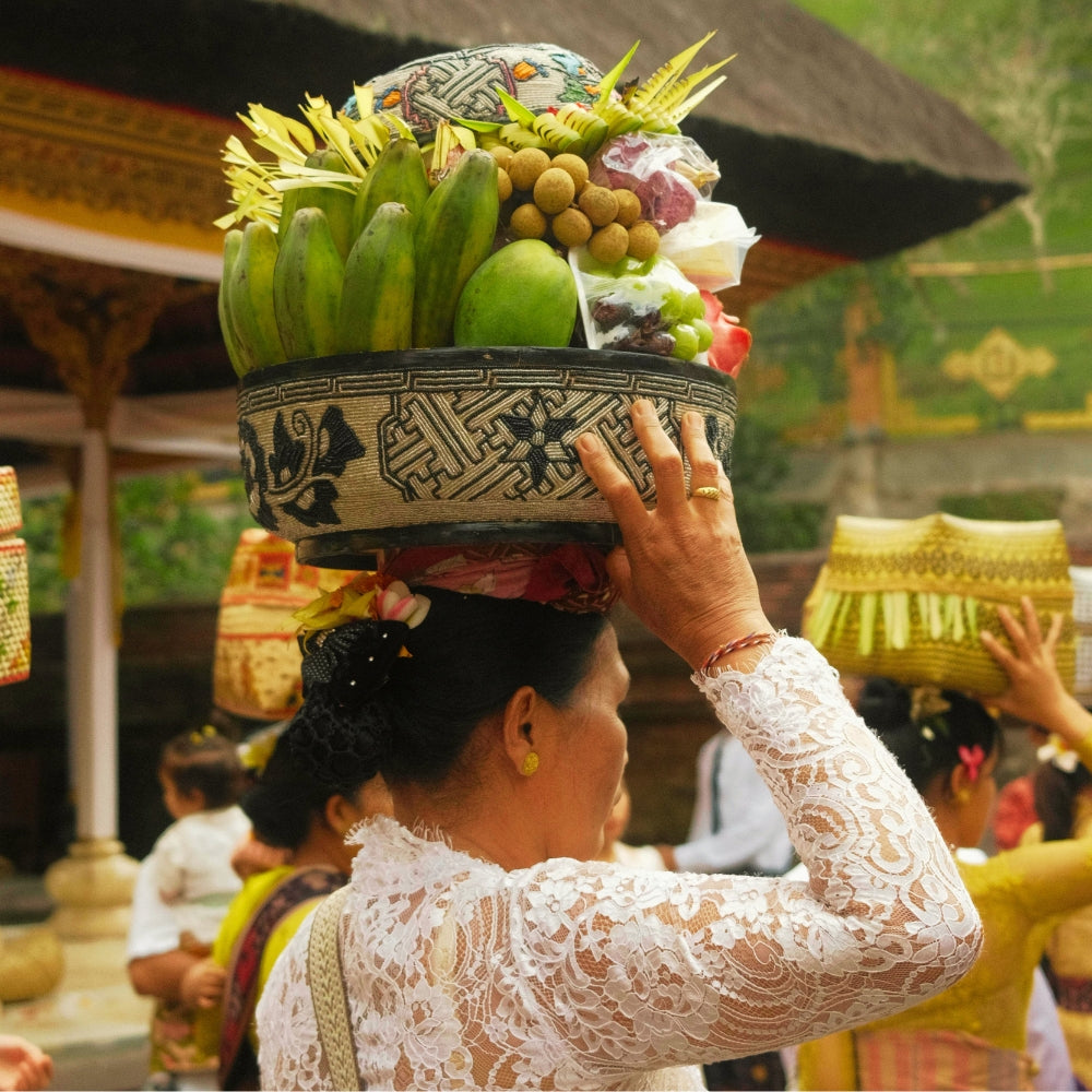 A local Balinese woman carrying a basket of fruit on her head in a local ceremony