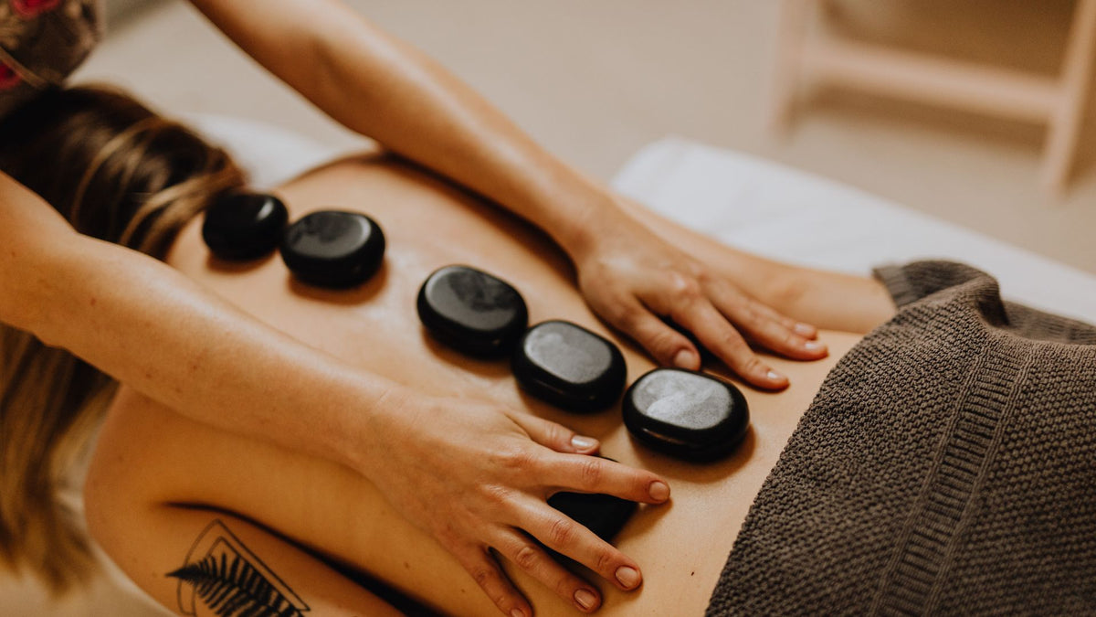 Person receiving a hot stone massage with stones on their back.