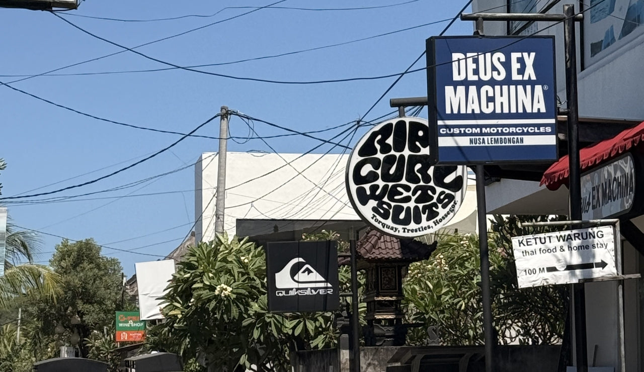 Quicksilver, Rip Curl and Deus Ex Machina Shop signs on the main street of Jungut Batu
