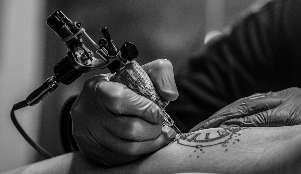 A tattoo gun tattooing on an arm 