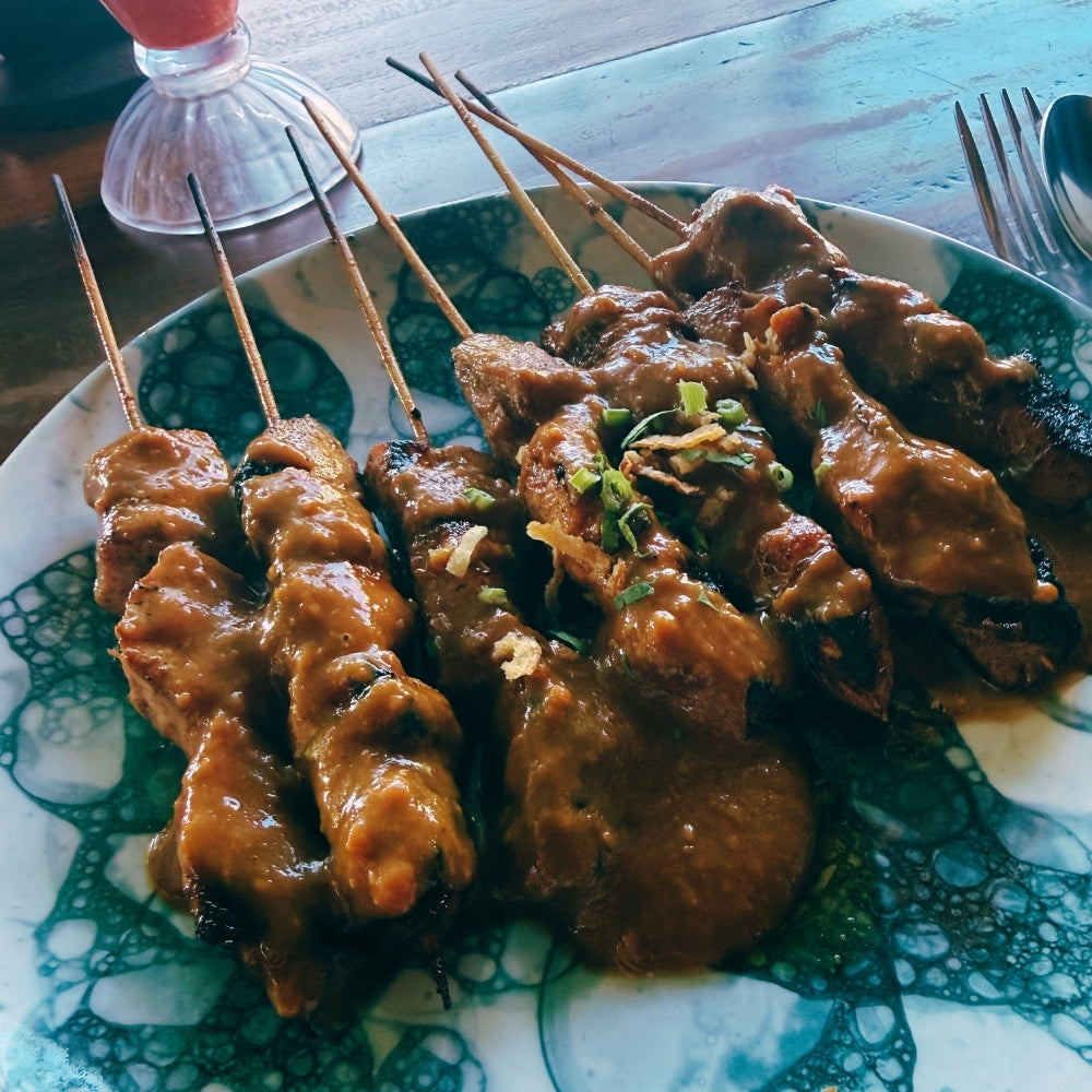 Skewered meat dish on a decorative plate with a blurred background, served at Warung Soka, Mushroom Bay
